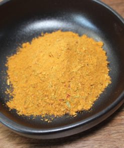 Bol de curry en poudre épicé sur une table en bois, idéal pour relever vos plats de cuisine maison.