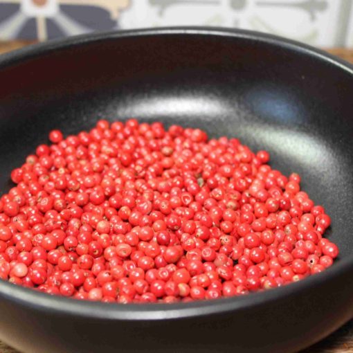 Assiette noire avec des baies rouges fraîches, prêtes pour la cuisine ou la décoration culinaire.