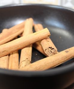 Bâtons de cannelle dans un bol noir : épice aromatique pour cuisiner ou infuser des boissons.