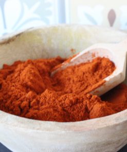 Paprika en poudre dans un bol en bois avec cuillère, parfait pour rehausser vos plats.